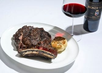 Steak on a plate with a glass of red wine